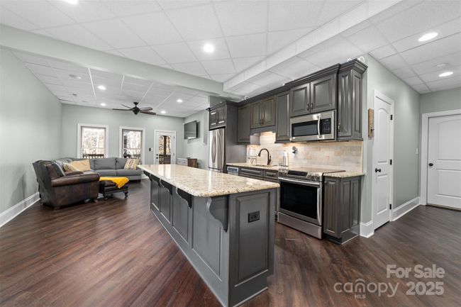 Fully finished basement with complete kitchen and granite countertops and island bar. | Image 23