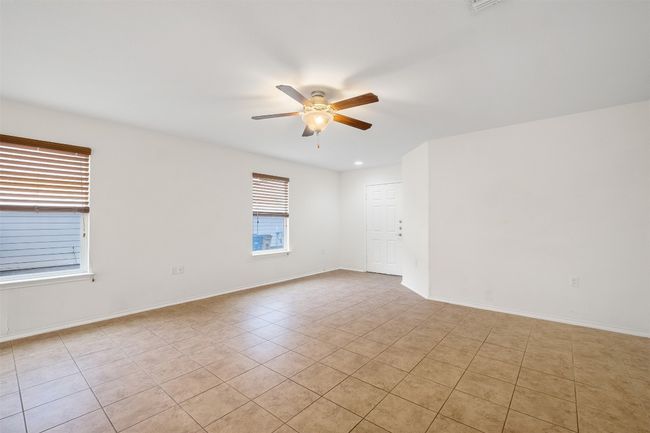 Empty room with light tile patterned floors, baseboards, and ceiling fan | Image 13