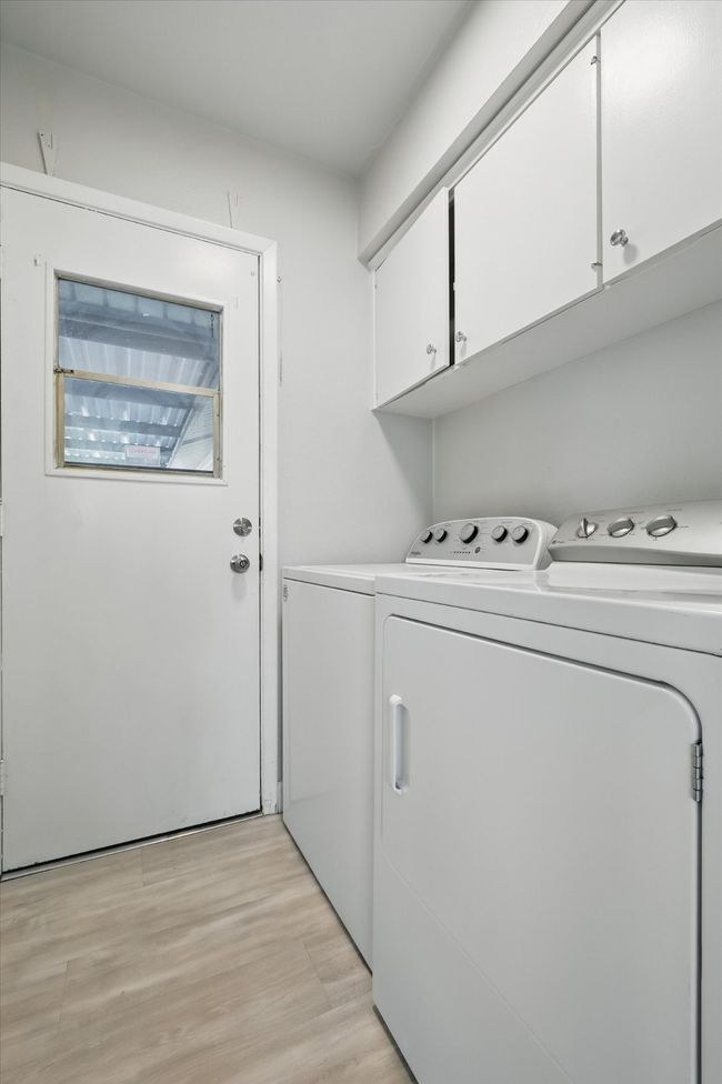 Clothes washing area with washing machine and dryer, light wood finished floors, and cabinet space | Image 18