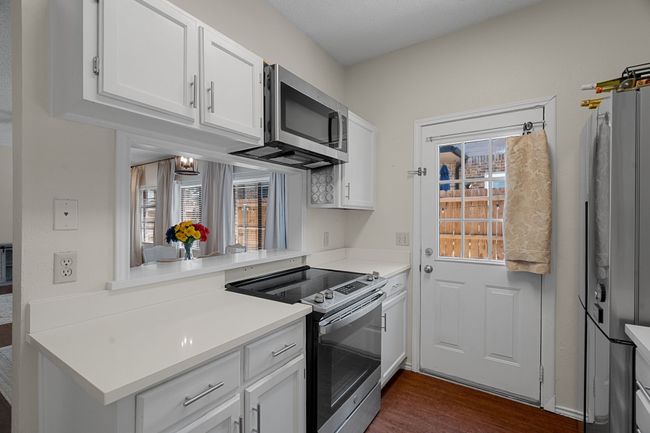 Kitchen with stainless steel appliances, white cabinets, dark wood-style flooring, and light countertops | Image 10