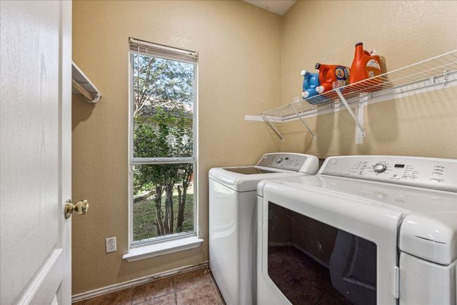 Clothes washing area featuring washing machine and dryer, a textured wall, tile patterned floors, and laundry area | Image 27