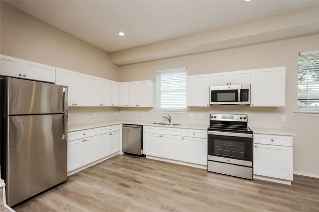 Kitchen featuring appliances with stainless steel finishes, white cabinetry, light countertops, light wood-type flooring, and recessed lighting | Image 9