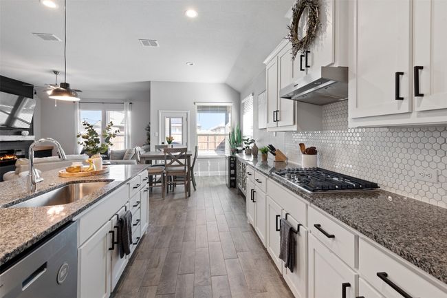 Kitchen featuring visible vents, dishwashing machine, range hood, stainless steel gas stovetop, and a sink | Image 14