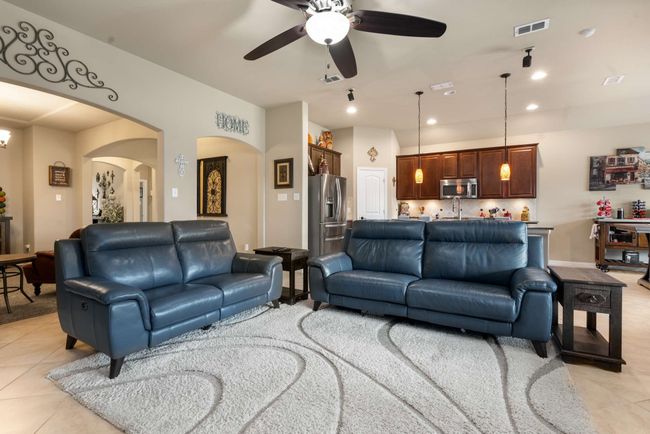 Living room with light tile patterned flooring, arched walkways, ceiling fan, and recessed lighting | Image 6