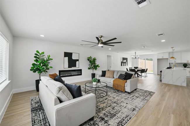 Living room with light wood-style flooring, a ceiling fan, a chandelier, baseboards, and recessed lighting | Image 5