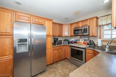 Kitchen featuring appliances with stainless steel finishes, sink, and a textured ceiling | Image 2