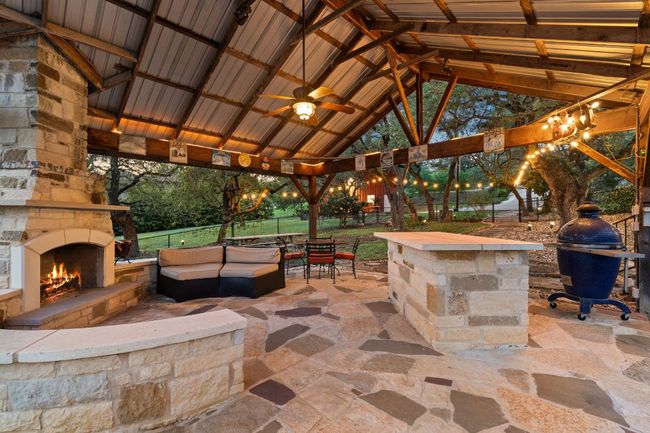 Covered outdoor living with fireplace and outdoor kitchen, strung with lights, overlooking the preserve. | Image 27