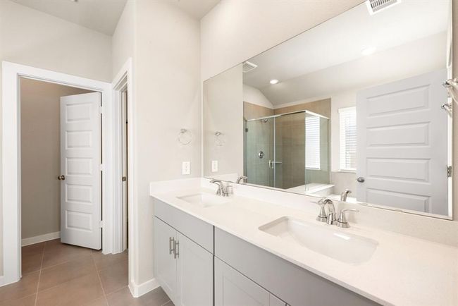 This primary bathroom is definitely move-in ready! Featuring a spa like walk-in shower with tile surround, separate garden tub for soaking after a long day with custom tile detailing, pebble cabinets with Quartz countertops, spacious walk-in closet with shelving, high ceilings, custom paint, sleek and modern finishes. | Image 10