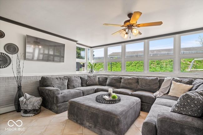 living area featuring light tile patterned flooring, a ceiling fan, and healthy amount of natural light | Image 10