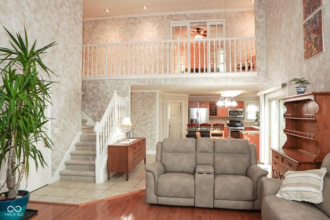 living area with light wood finished floors, ceiling fan, trendy paint throughout, stairway, and ornamental molding | Image 16
