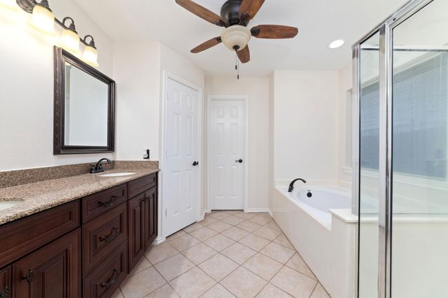 Open and airy primary bathroom featuring elegant cherrywood finishes, abundant natural light, and direct access to a spacious walk-in closet. | Image 23