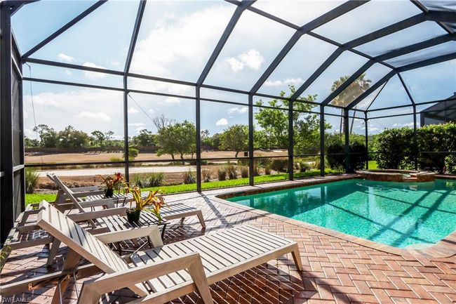View of swimming pool with a patio, a pool with connected hot tub, and a lanai | Image 26