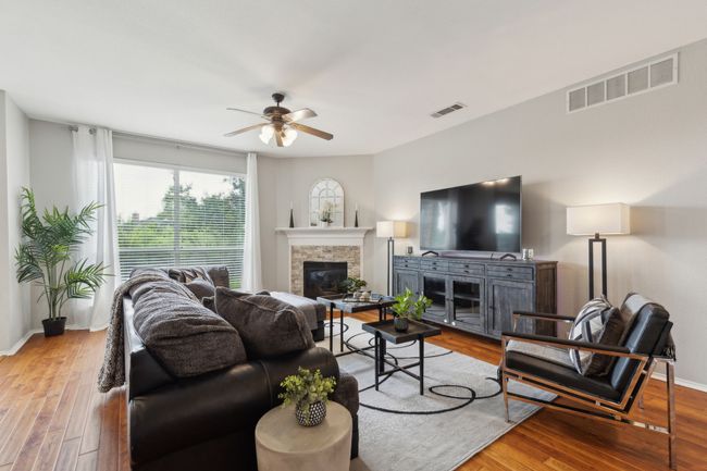 Living room featuring a glass covered fireplace, ceiling fan, wood finished floors, and baseboards | Image 11