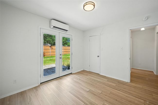Empty room featuring a wall mounted AC, french doors, a smoke detector, and light wood-style floors | Image 16