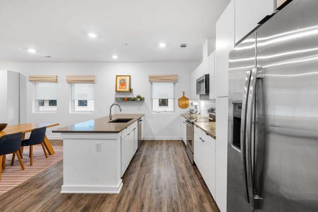 Kitchen with white cabinets, a peninsula, modern cabinets, appliances with stainless steel finishes, and a sink | Image 13