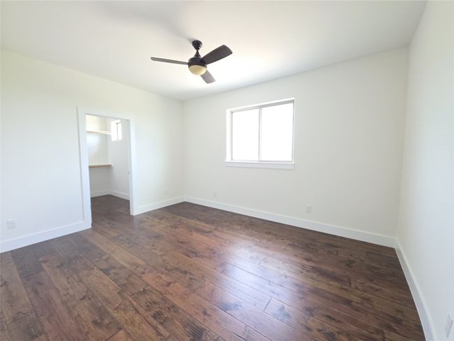 Unfurnished bedroom featuring dark wood-type flooring, a walk in closet, and baseboards | Image 24