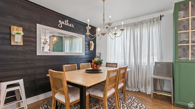 Dining room with wood finished floors, wood walls, and a notable chandelier | Image 5