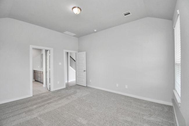 Escape and relax in the exquisite primary suite, a haven to unwind after a long day. The spacious room, boasts plush carpeting, soothing paint tones, high ceilings, and expansive windows adorned with privacy blinds. | Image 25