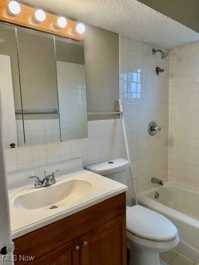 Bathroom featuring vanity, tile walls, toilet, and a textured ceiling | Image 15