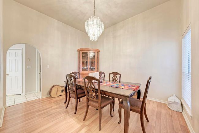 Dining area featuring arched walkways, light wood finished floors, a chandelier, and baseboards | Image 15