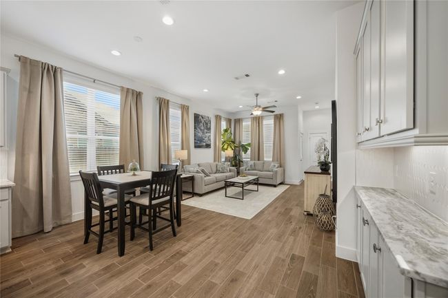 The dining room features elegant lighting, soft natural tones, and side yard views through tall windows, creating the perfect setting for dinner parties or cozy family meals. | Image 12