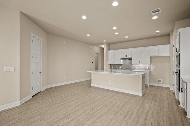 Kitchen with visible vents, white cabinetry, decorative backsplash, light wood-style floors, and appliances with stainless steel finishes | Image 6
