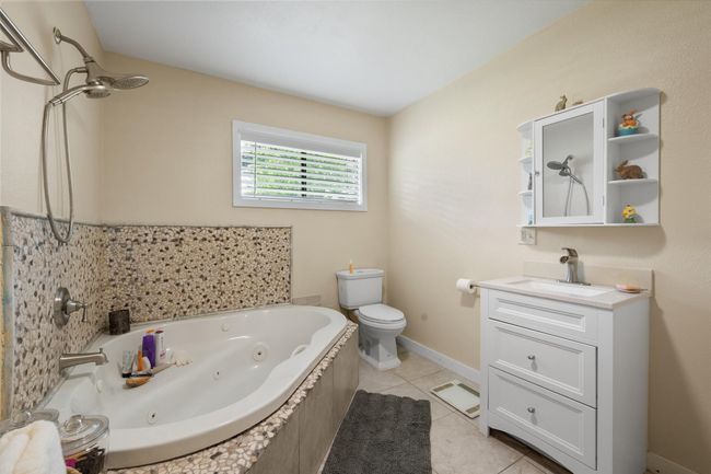 Full bathroom with toilet, a tub with jets, vanity, and tile patterned floors | Image 38