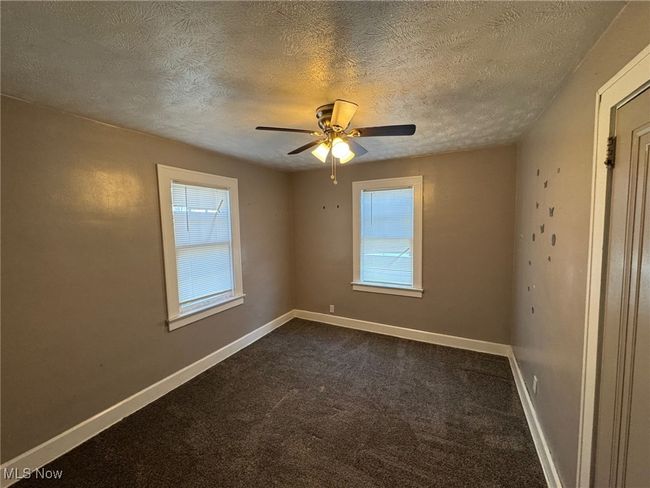 Bedroom with a textured ceiling, a healthy amount of sunlight, a ceiling fan, and dark carpet | Image 13