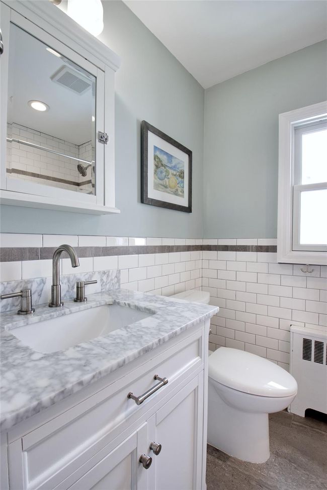Full bath with radiator heating unit, vanity, toilet, tile walls, and a wainscoted wall | Image 8