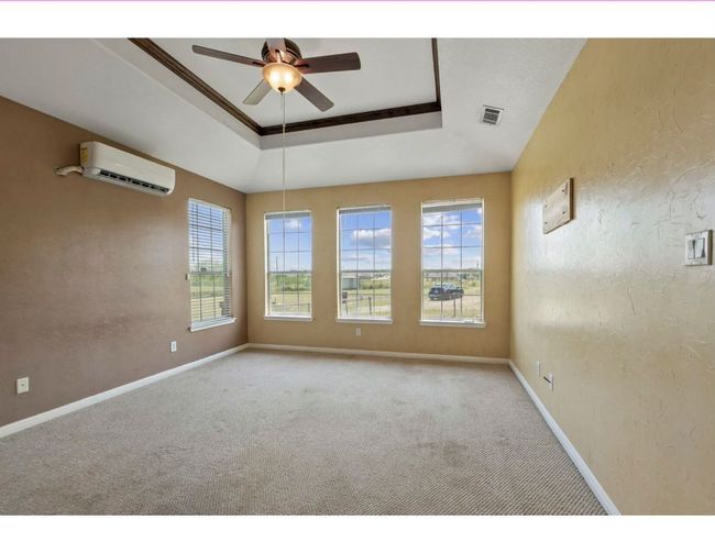 Unfurnished room with a tray ceiling, a textured wall, carpet floors, a ceiling fan, and a wall unit AC | Image 10