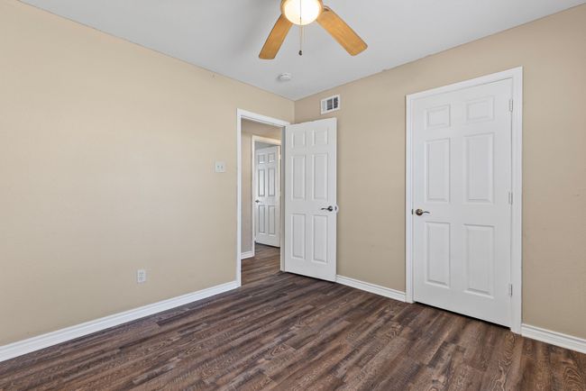 Unfurnished bedroom with dark wood-type flooring, a ceiling fan, visible vents, and baseboards | Image 23