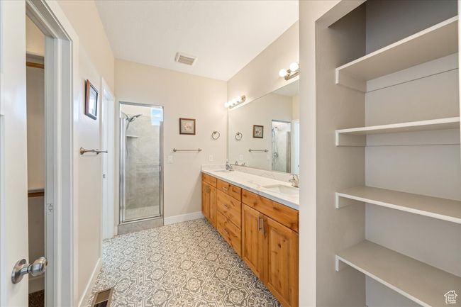 Bathroom featuring double vanity, a sink, visible vents, and a stall shower | Image 25