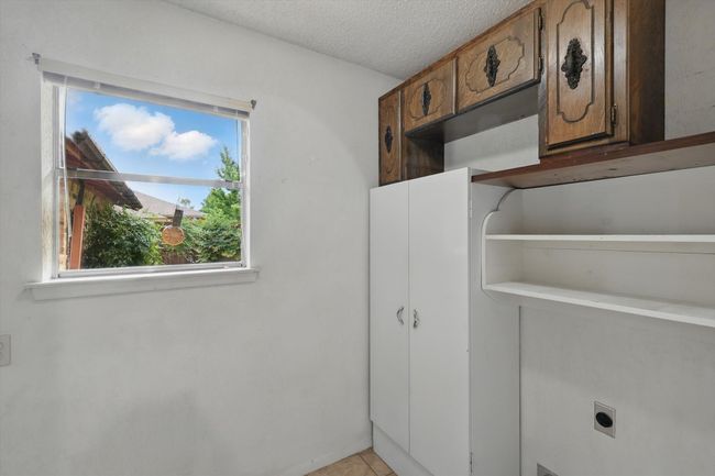 Laundry area with electric dryer hookup, a textured ceiling, and light tile patterned floors | Image 23