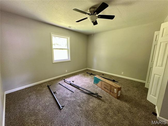 Empty room with a textured ceiling, a ceiling fan, and carpet flooring | Image 10