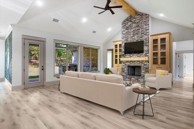 Living room with beam ceiling, ceiling fan, high vaulted ceiling, a brick fireplace, and light wood-style flooring | Image 28
