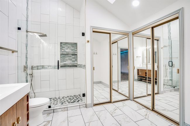 Full bath featuring marble finish flooring, a stall shower, vaulted ceiling, vanity, and toilet | Image 21