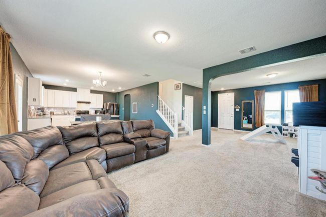 Living area with arched walkways, a chandelier, light colored carpet, stairway, and recessed lighting | Image 13