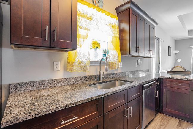 Kitchen featuring dishwasher, stone countertops, light wood finished floors, and dark brown cabinetry | Image 10