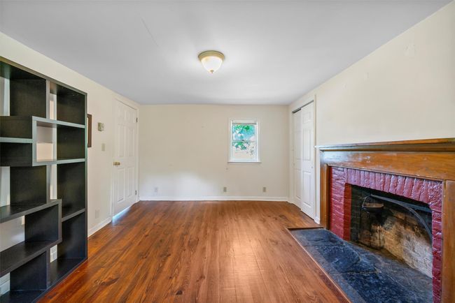 Unfurnished living room featuring wood finished floors, a brick fireplace, and baseboards | Image 13