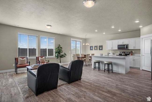 Living area with baseboards, dark wood-style floors, recessed lighting, a textured ceiling, and a notable chandelier | Image 4