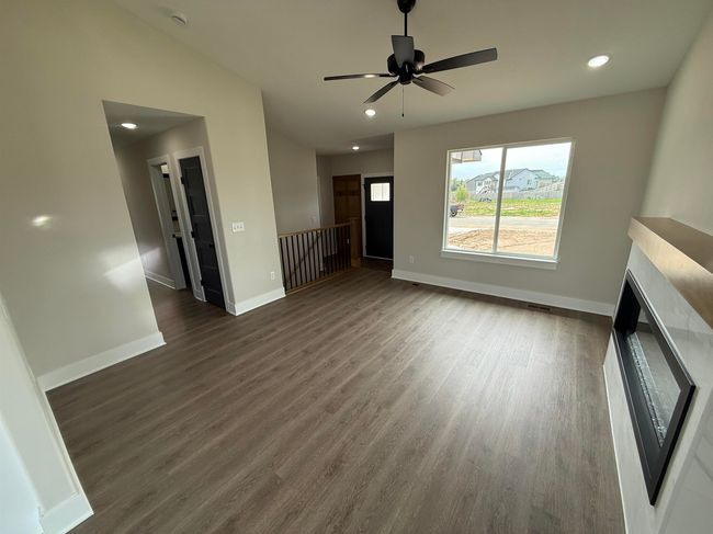 Unfurnished living room featuring dark wood finished floors, baseboards, recessed lighting, ceiling fan, and a fireplace | Image 6
