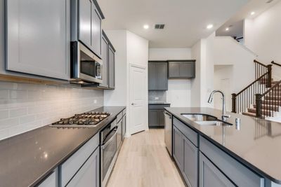 Kitchen featuring sink, gray cabinetry, stainless steel appliances, light hardwood / wood-style floors, and decorative backsplash | Image 3