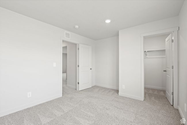 Unfurnished bedroom with carpet flooring, a walk in closet, a closet, and recessed lighting | Image 37
