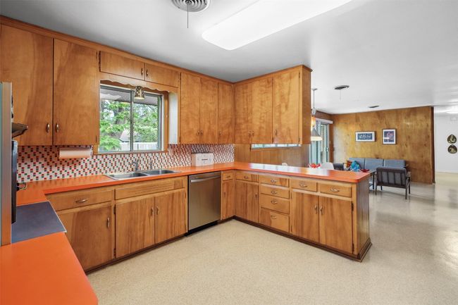 Kitchen featuring a peninsula, dishwasher, open floor plan, a sink, and backsplash | Image 16