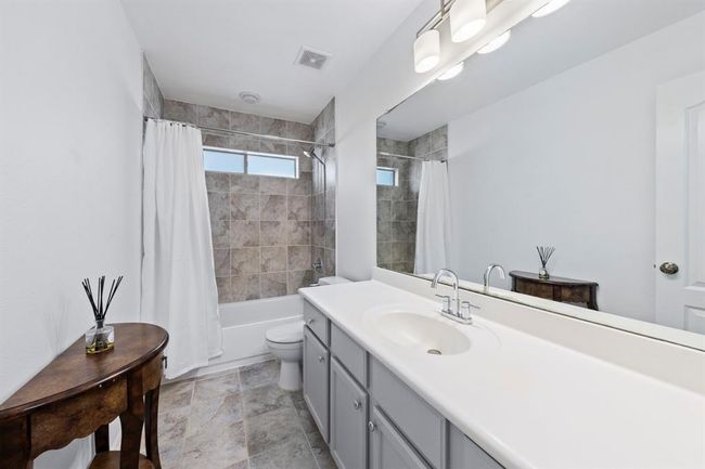 This secondary bathroom offers a clean, modern aesthetic with a tiled shower/tub combo, extended vanity, and ample storage. | Image 17