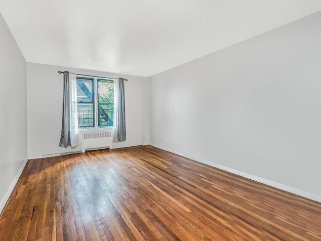 Unfurnished room featuring radiator heating unit and wood finished floors | Image 9