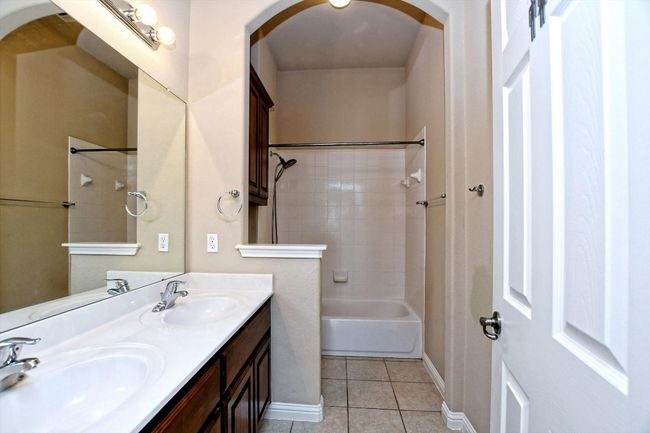 Full bath featuring tile patterned flooring, baseboards, double vanity, and bathtub / shower combination | Image 24