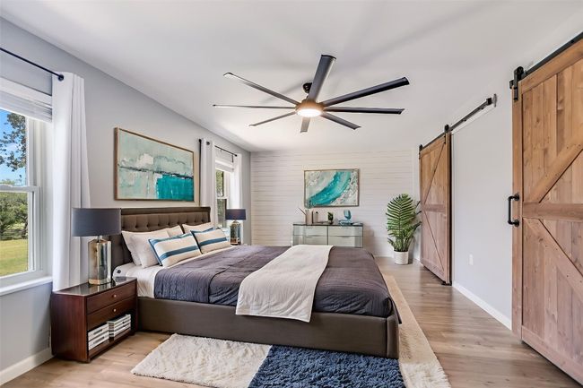 Bedroom with a barn door, light wood finished floors, and ceiling fan | Image 17