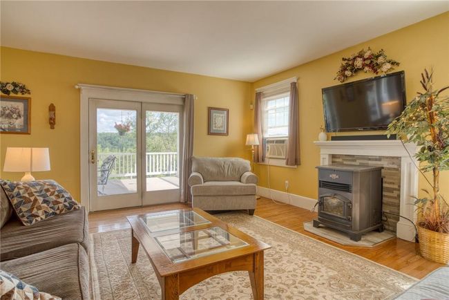 Living room featuring a wood stove, light hardwood / wood-style flooring, a wealth of natural light, and cooling unit | Image 6