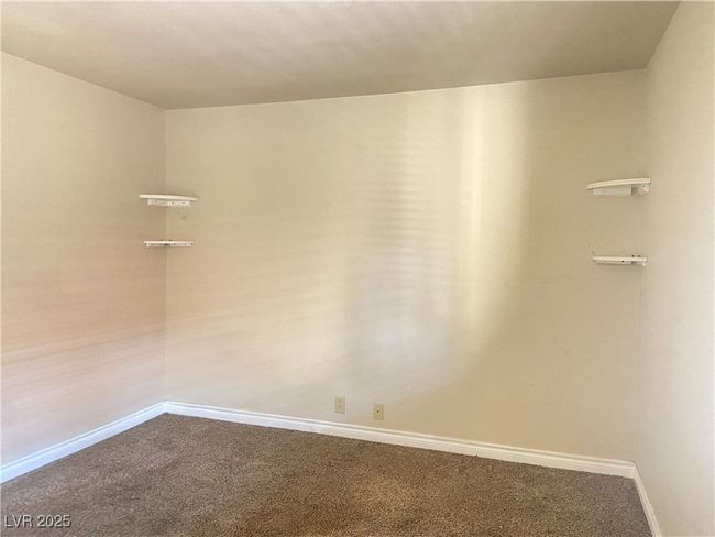Empty room featuring baseboards and dark colored carpet | Image 15